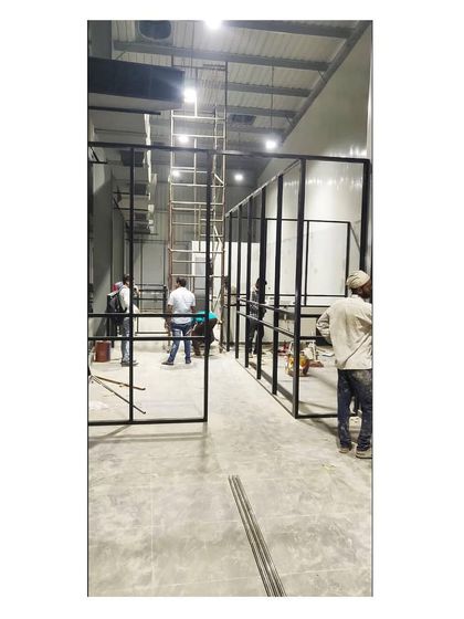 Workers installing the black metal framework for the office partitions. This image shows the raw construction and precision required to achieve the final sleek design.