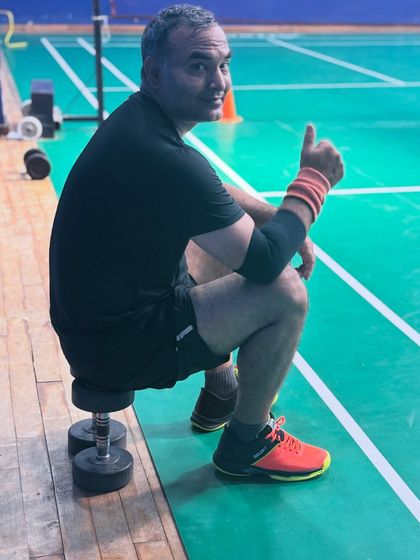 Mixing strength with shuttle. Even light weights can be used to stay sharp, mobile, and match-ready. Here a player takes a quick break on some dumbbells.