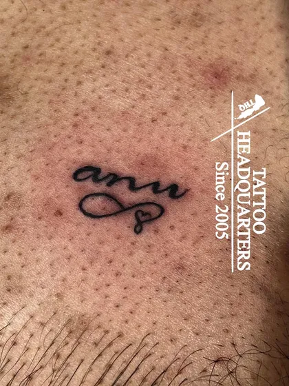 A small name tattoo "anu" with an infinity heart symbol, a delicate and personal piece.