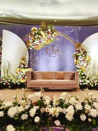 A wide view of our floral reception stage, featuring a stunning arch and elegant paneling. The design is both grand and intimate, perfect for capturing beautiful moments.