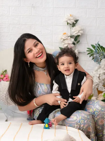 A joyful mother and son portrait. Her radiant smile and his happy expression are the heart of this beautiful image, set against a backdrop of white flowers.