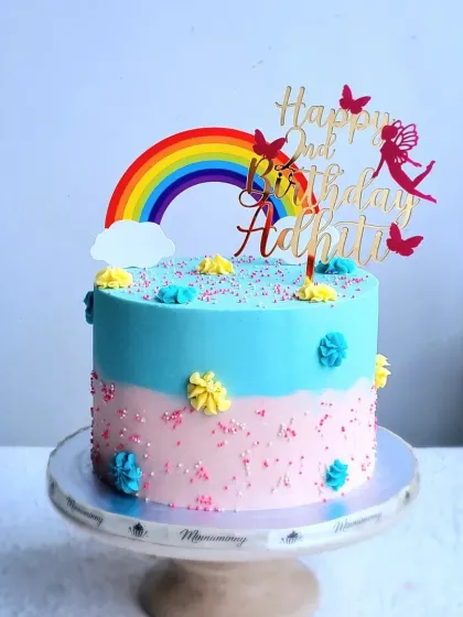 A full view of the two-tone rainbow cake on its stand.