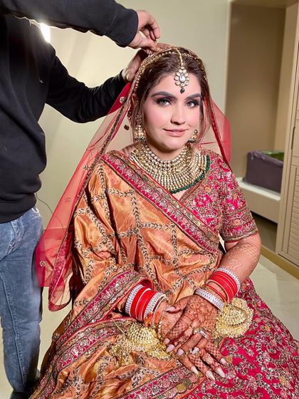 A candid moment during the final touches, as the hairstylist sets the dupatta on her head.