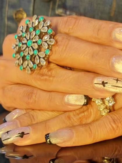 A modern and edgy French manicure with black tips and a shimmery white base, featuring minimalist heart and star line art.