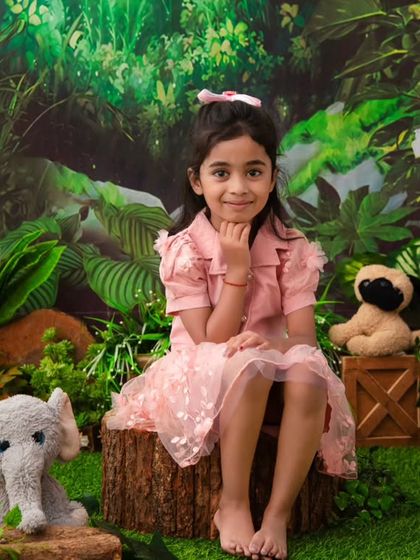 A jungle princess. This older sister poses beautifully in a lush jungle setting, complete with her favorite stuffed animals.