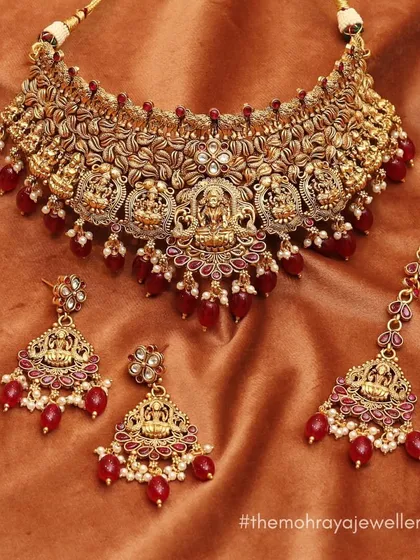 A beautiful temple jewellery set with a choker and matching earrings, featuring goddess motifs and red bead drops. Perfect for a traditional South Indian bridal look.