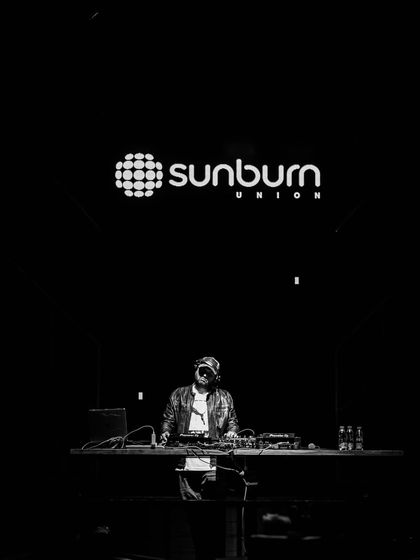 A dramatic black and white shot of me at the console at Sunburn Union, with the club's logo glowing above.