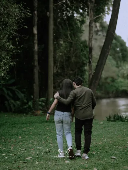 The couple walking away together, his arm around her, into the serene beauty of a forest path.
