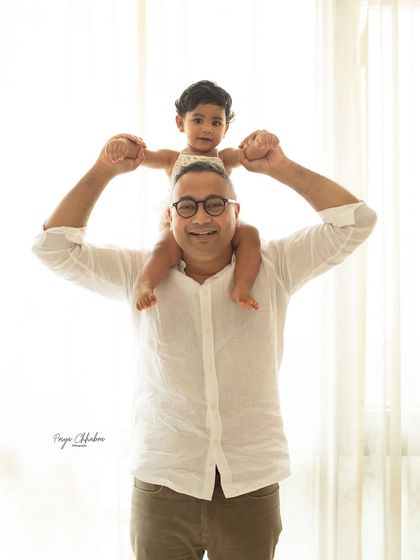 Adventures with daddy! A father holds his daughter up on his shoulders, a classic and joyful pose that's perfect for any family or milestone photoshoot.