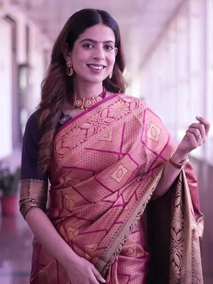 A smiling portrait in a traditional pink and gold silk saree.