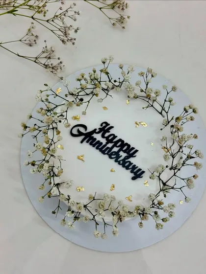 Pure elegance, timeless love. A minimalist white anniversary cake adorned with a wreath of baby's breath.