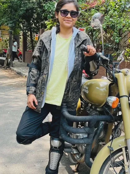 A graduate in full gear, standing proudly with her bike. She is ready for any adventure the road may bring.