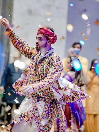A dancer is showered with confetti, his arms raised in celebration, capturing a peak moment of the Navratri festivities.