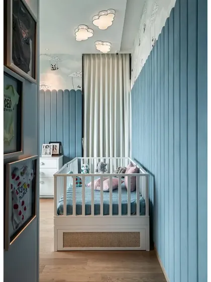 Another angle of the nursery, showing the cloud-shaped ceiling lights and the framed baby clothes on the wall, adding a personal and sentimental touch.