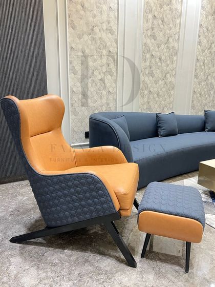 A close-up of the tan and blue-grey leather wingback chair. The combination of smooth tan leather and quilted, textured fabric on the sides and back showcases our attention to material detail.