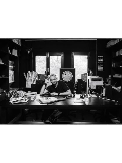 A wide shot of artist Pushkar Thakur in his studio, surrounded by his work. This black and white environmental portrait tells the story of his creative world.