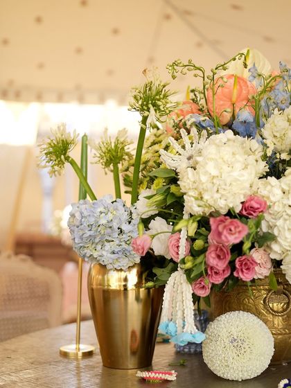 Another unique centerpiece with a variety of textures and colors, including pink roses, blue hydrangeas, and green anthuriums.
