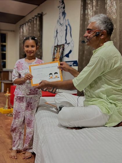 A young girl in her pajamas receives her certificate, marking the end of a wonderful week of yoga, games, and community.