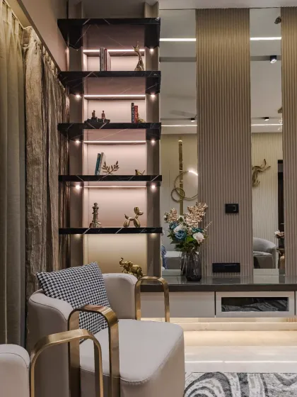 A perfect blend of modern luxury and artistic refinement. This living space features a sculptural accent chair with gold metallic arms and sleek, marble-detailed shelving with integrated lighting. Every detail is curated to enhance depth, warmth, and timeless charm.