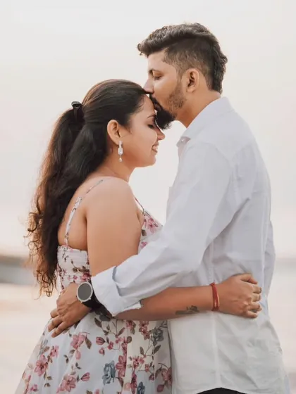 A tender kiss on the forehead against the backdrop of the sea at sunset. This is a classic romantic pose that never fails to capture the love and affection between a couple during their beach pre-wedding shoot.
