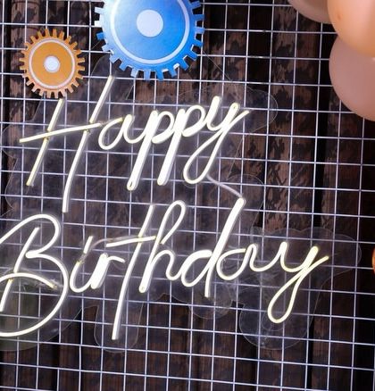 A "Happy Birthday" neon sign against a wire mesh panel adds an industrial touch to our robot-themed decor.