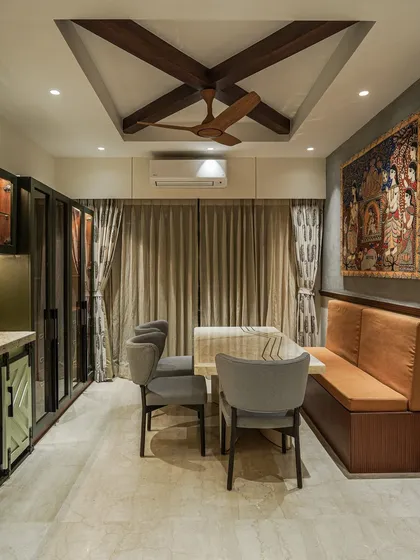A dining area with bench seating, where a Pattachitra painting hangs above, blending farmhouse charm with Indian art.