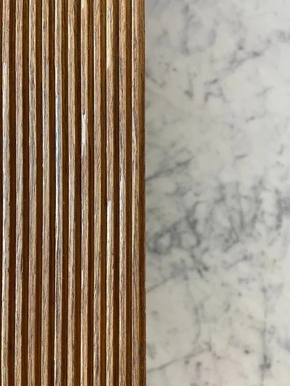 A material study showing classic fluted wood against the rich pattern of Carrara white marble. We often explore these juxtapositions to create a refined and tactile interior palette.