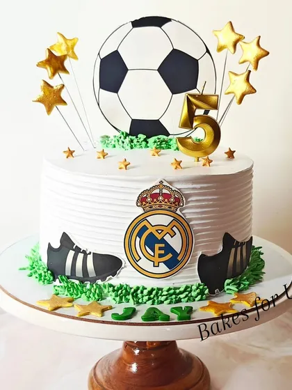 A Real Madrid-themed football cake for a 5th birthday, decorated with the team's crest, a large soccer ball, and golden stars.