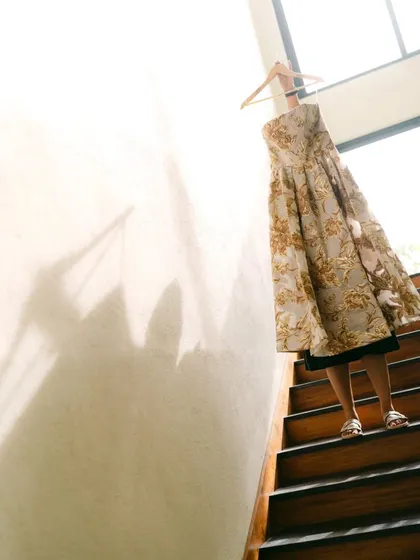 An artistic shot of the bride's wedding dress hanging on a staircase. The play of light and shadow creates a beautiful, abstract image full of anticipation.