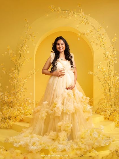 Bathed in sunshine yellow, this portrait is pure joy. The mother-to-be stands in a stunning architectural archway adorned with matching yellow flowers, creating a bright and happy scene.