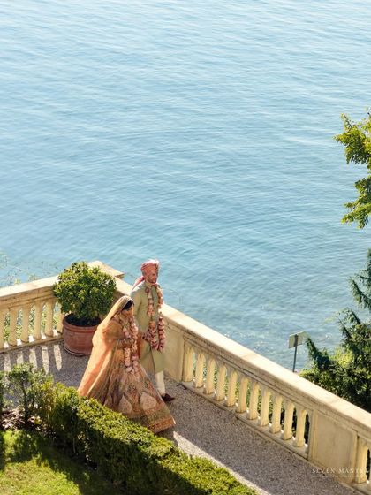 The couple walking along the beautiful Italian coast. This wide shot captures the scale and beauty of their destination wedding.