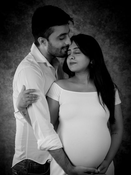 A tender black and white portrait. The partner gently kisses his partner's forehead, creating a soft, emotional, and timeless image of their connection.