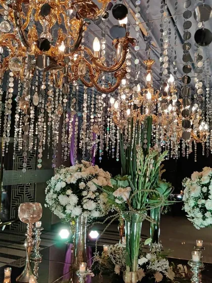 A beautiful composition showing the shimmering ceiling, a grand chandelier, and elegant white floral arrangements, capturing the luxurious essence of the sangeet decor.