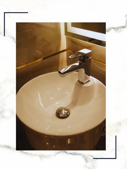 A close-up of a modern, minimalist faucet on a white vessel sink. This shot highlights the quality of the fixtures we use, which are chosen for both their design and their durability.