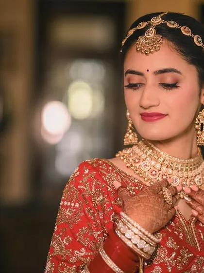 A soft and elegant portrait of the bride adjusting her necklace. This highlights the exquisite jewelry and the delicate details of her henna-adorned hands.