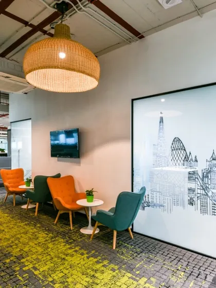 A small lounge area with colorful armchairs and a large, framed graphic of the London skyline. The textured yellow and grey carpet adds visual interest.