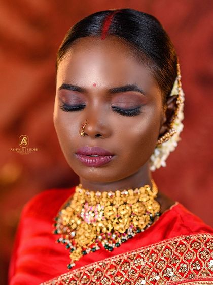 A close-up beauty shot focusing on the eye makeup of a traditional bridal look. The lighting is carefully controlled to highlight the shimmer on the eyelids and the richness of the lip color.