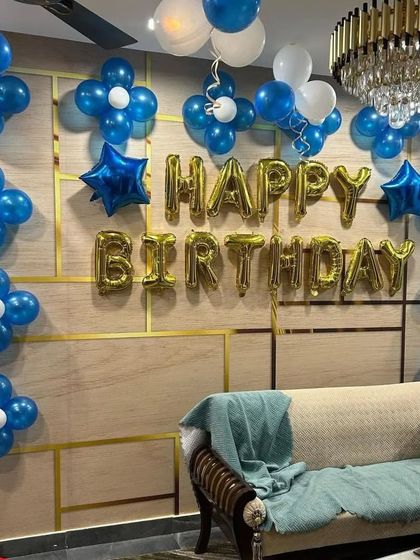 A simple and elegant living room decoration with blue and white balloon flowers and a gold "Happy Birthday" foil banner.