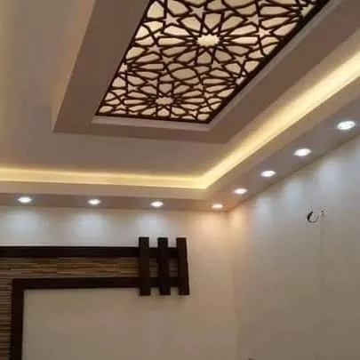 A simple yet elegant design featuring a large, rectangular backlit jali panel. The warm cove lighting around the perimeter adds to the sophisticated and cozy atmosphere.