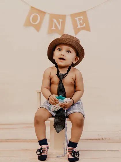 A sweet portrait of a baby boy looking up, with a 'ONE' banner in the background marking his first birthday.