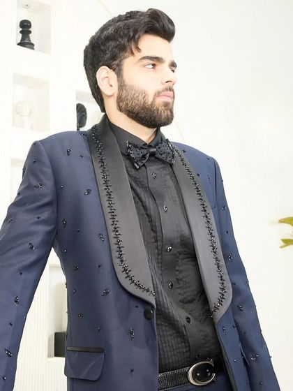 A detailed shot of the navy blue tuxedo, focusing on the hand-embroidered lapels and the matching embellished bow tie. Every detail is meticulously crafted.