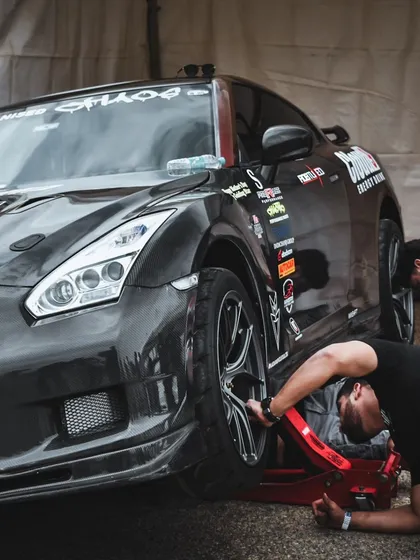The pit crew works on a heavily modified Nissan GTR, a common sight in the high-stakes world of professional drag racing.