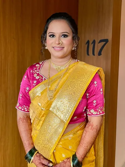 This bride is radiating timeless elegance in her yellow and pink Paithani saree. The makeup is soft and defined, with kohl-rimmed eyes and a delicate glow.