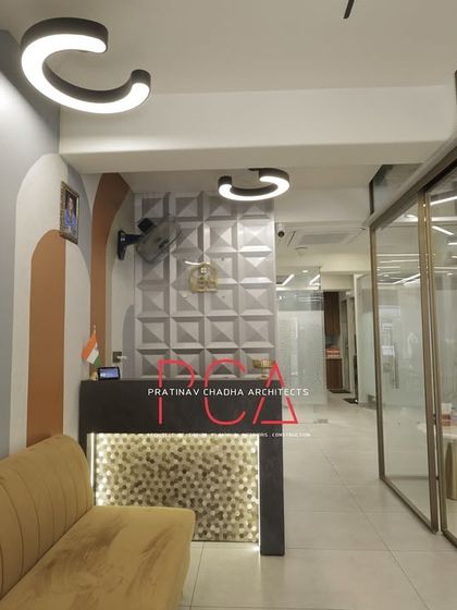 This view shows the reception area leading into the main office, with glass partitions that maintain an open feel while defining separate functional zones. The curved lighting fixtures echo the arched patterns on the wall.