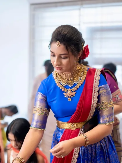 A candid shot showing the client during her ceremony, her traditional hairstyle adorned with a red rose.