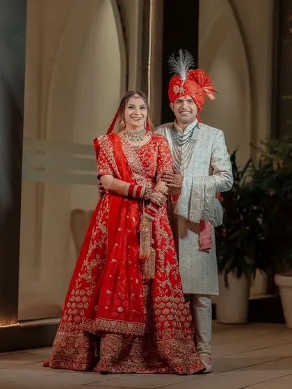 A classic full-length portrait of Lokesh and Kritika, showcasing their stunning wedding attire and the elegance of their pairing.