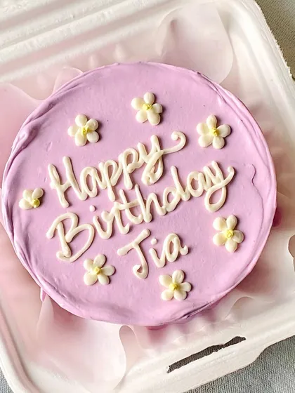 A lovely lavender bento cake with delicate white piped flowers and a "Happy Birthday" message. These mini cakes are perfect for a personal and thoughtful gift.