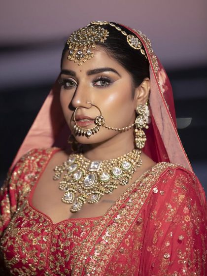 A profile shot of a bride, highlighting the clean lines of her bridal bun and how it supports the maang tikka and dupatta. This is a timeless and elegant wedding day hairstyle.