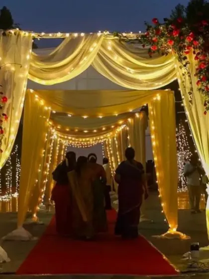 We create magical entrances that set the tone for your entire event. This beautiful walkway, draped in soft yellow fabric and illuminated by hundreds of fairy lights, provides a grand and welcoming passage for your guests.