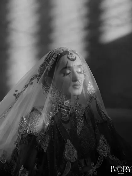 A serene black and white portrait of the bride with her eyes closed, enveloped by her veil. The play of light creates a peaceful and angelic feel.